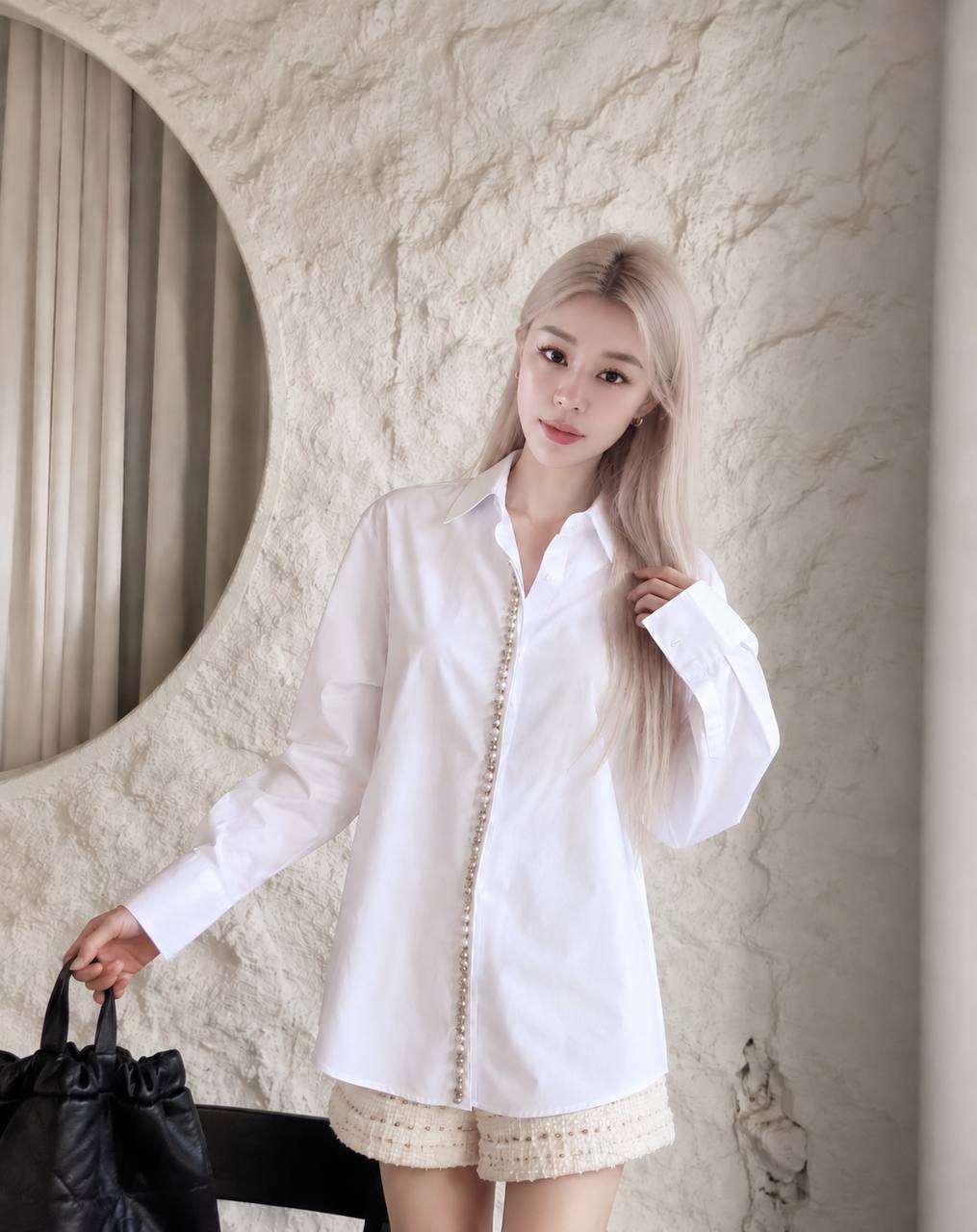 Wiwi wearing an ivory outfit beside a sculpted stone wall